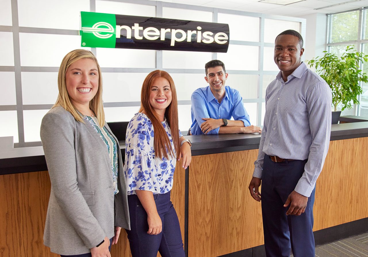 Man and woman talking on a sunny day at the rental car lot.