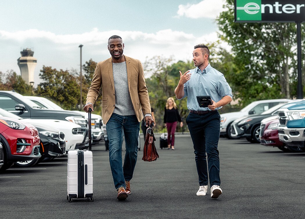 An employee and customer talk as they walk through an Enterprise Rent-A-Car lot